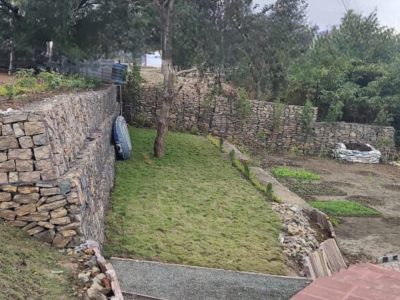 Several Indian construction workers are pouring and leveling concrete for a road or pathway, using a large wooden screed.
